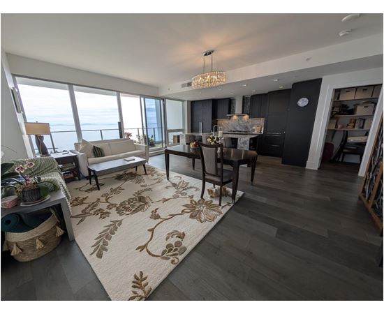 A living room with a rug on the floor and a dining table with chairs.
