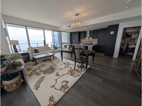 A living room with a rug on the floor and a dining table with chairs.