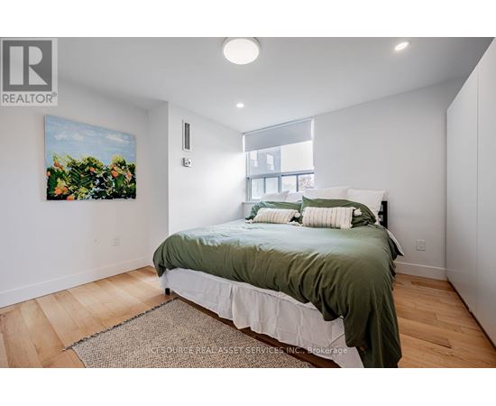 A bedroom with a bed, a rug, and a painting on the wall.