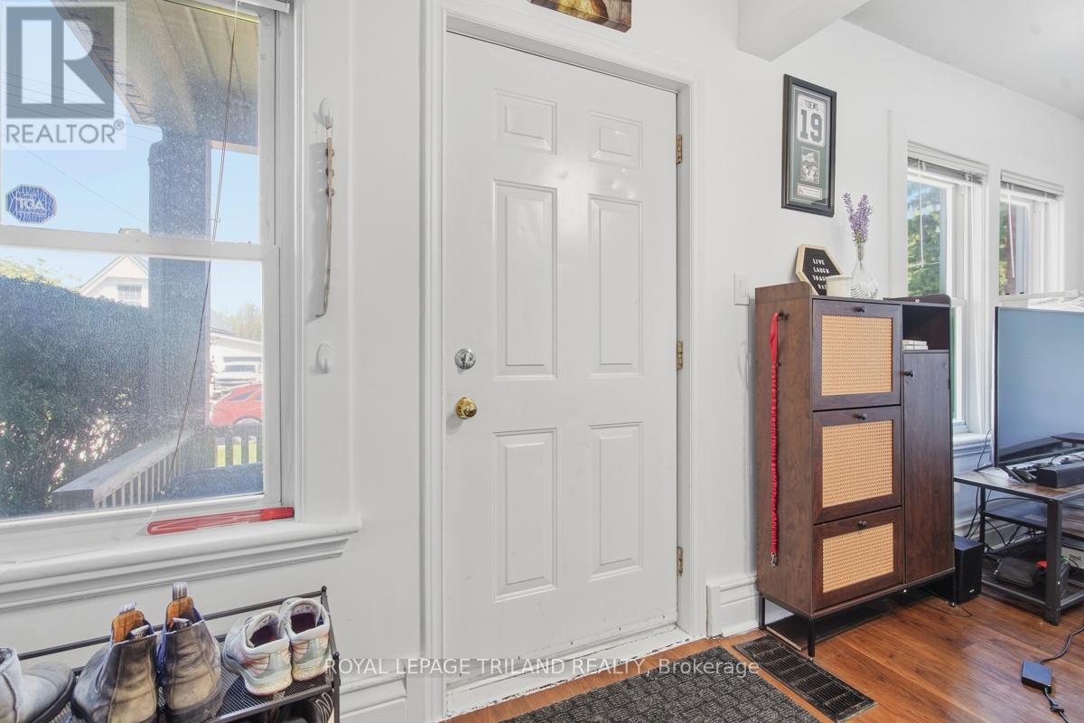 A white door is in a room with a shoe rack and a cabinet.