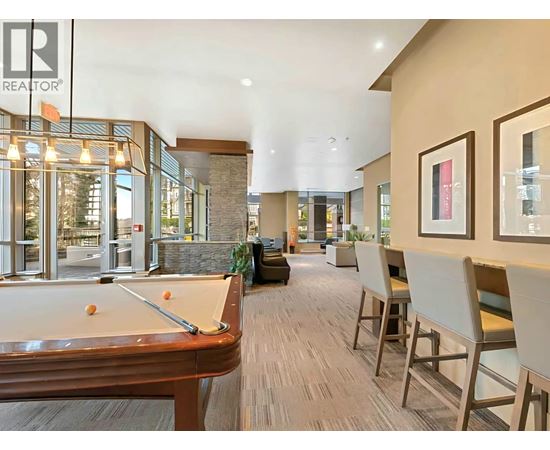 A pool table is in the middle of a room with chairs around it.