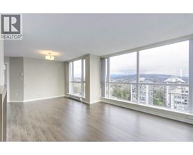 A spacious room with a view of the cityscape through large windows.