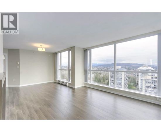 A spacious room with a view of the cityscape through large windows.