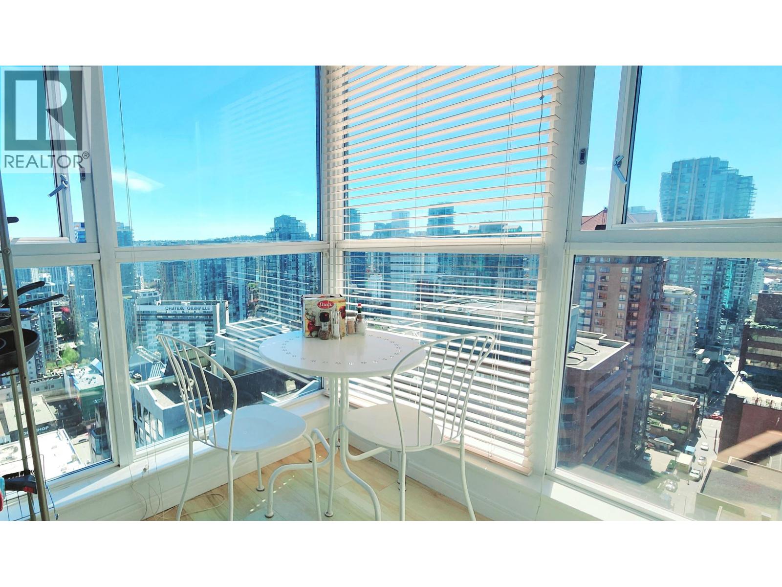 A table with chairs is in front of a window with blinds.