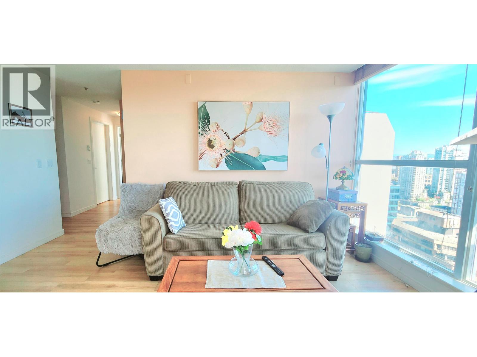 A living room with a grey couch, a coffee table, and a painting on the wall.
