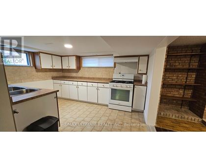 A kitchen with white cabinets and a brick wall.