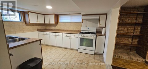 A kitchen with white cabinets and a brick wall.