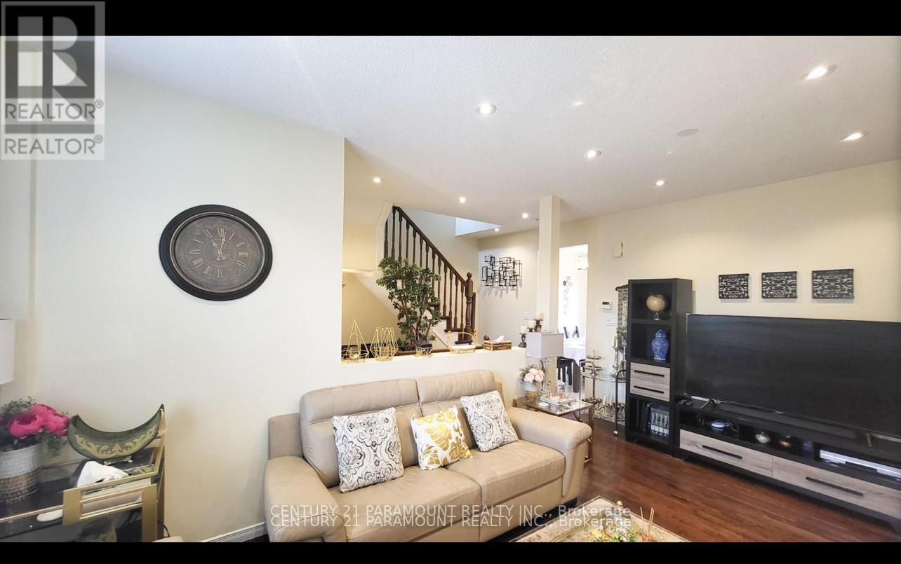 A living room with a couch, a television, and a staircase in the background.