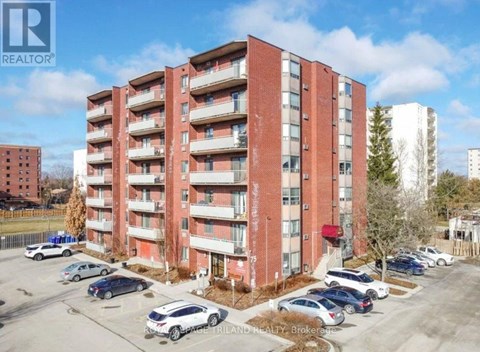 A large red brick apartment building with a parking lot in front.