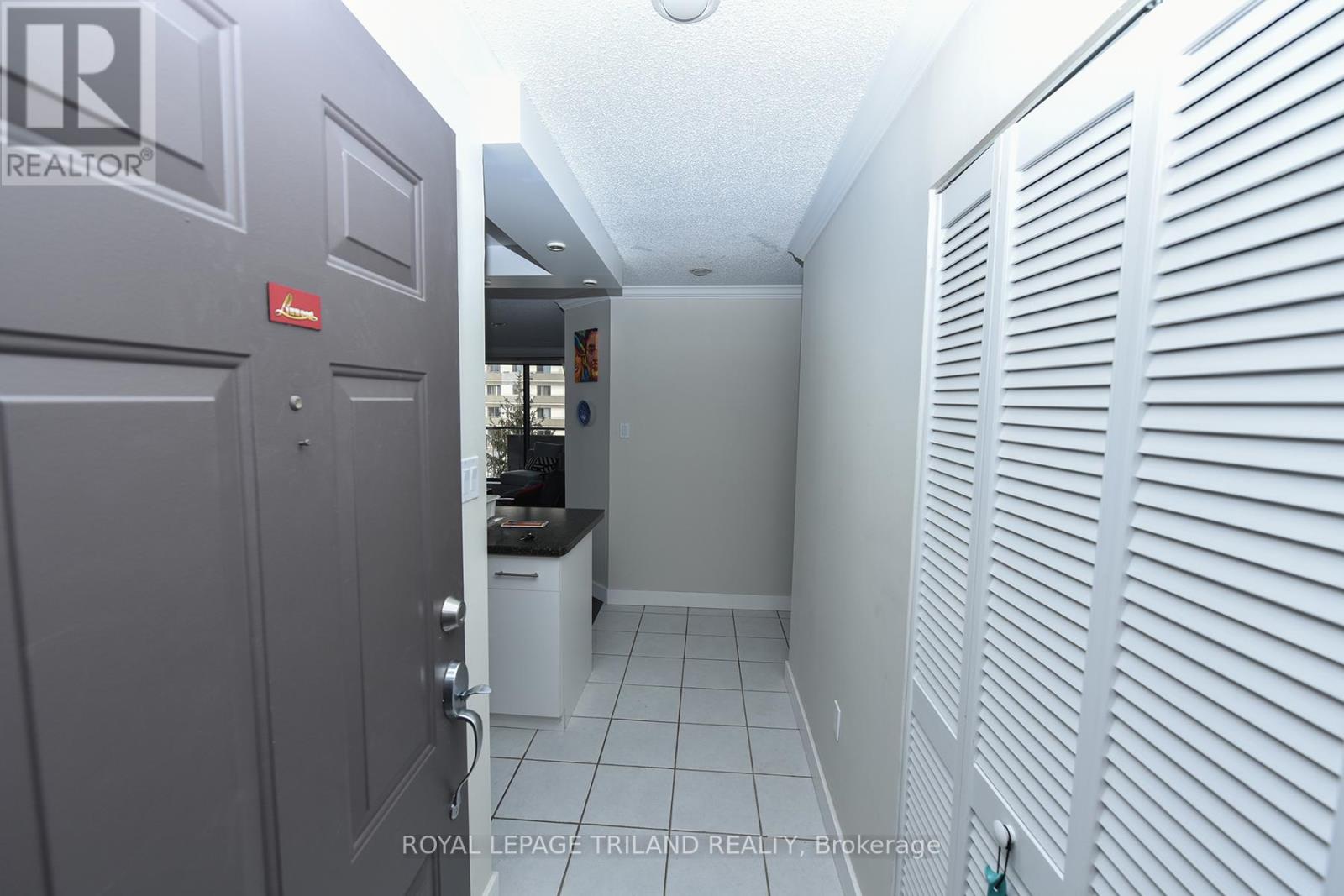 A hallway with a door on the left and a white shutter on the right.