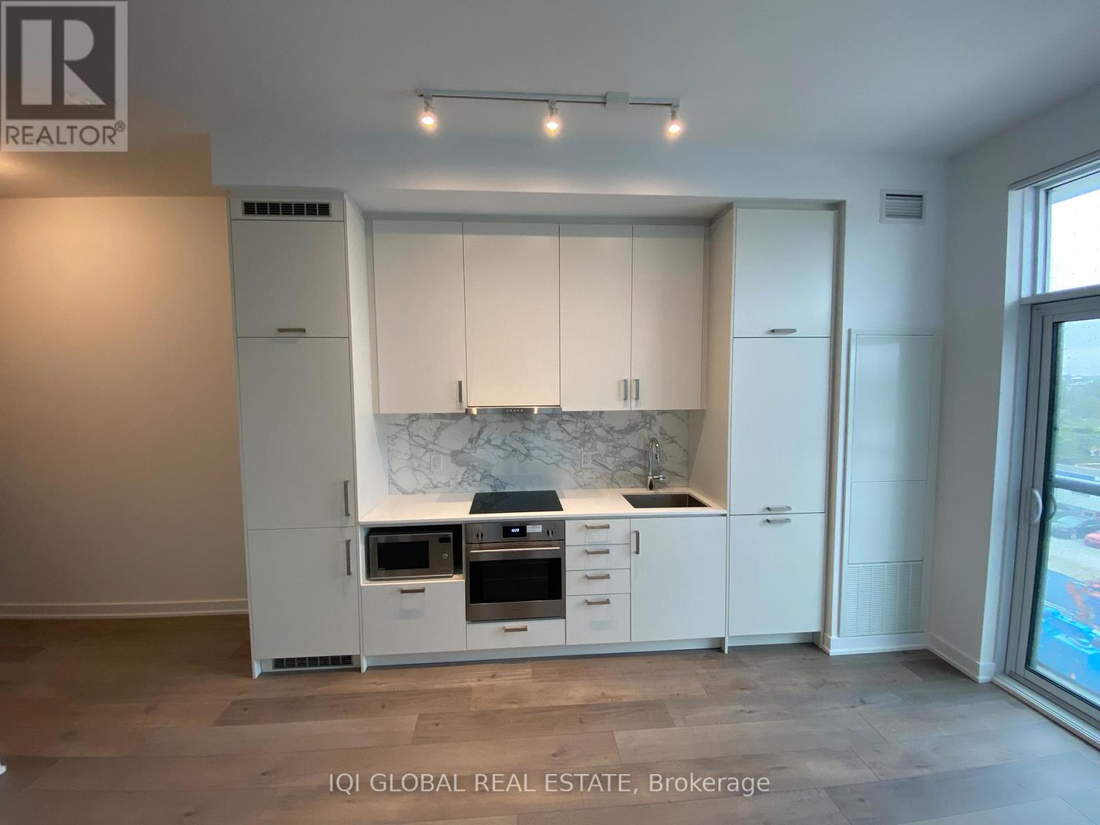 A modern kitchen with white cabinets and appliances.