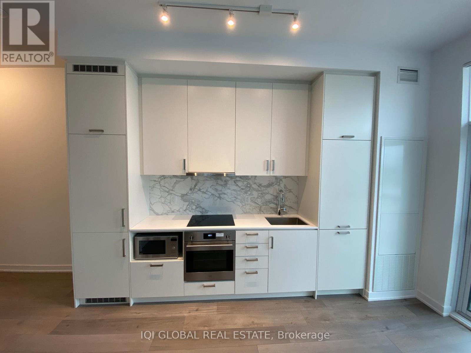 A modern kitchen with white cabinets and a marble backsplash.