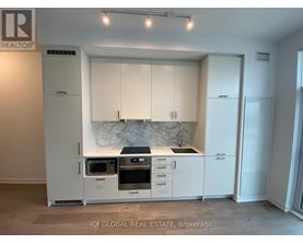 A modern kitchen with white cabinets and a marble backsplash.