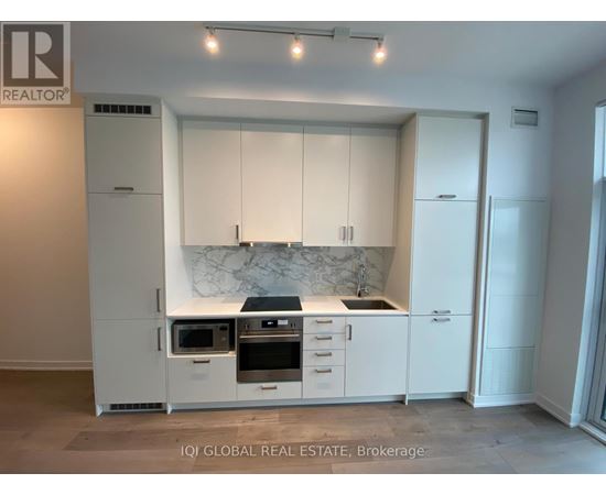 A modern kitchen with white cabinets and a marble backsplash.