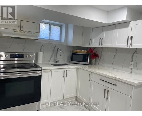 A kitchen with white cabinets and a marble backsplash.