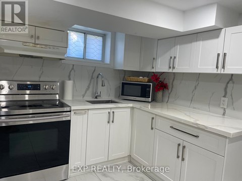 A kitchen with white cabinets and a marble backsplash.