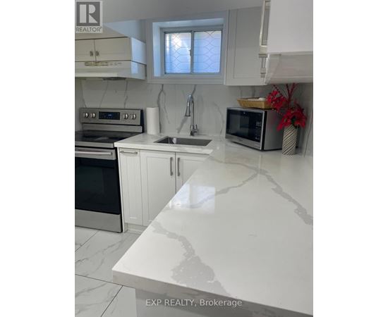 A kitchen with white cabinets and a marble countertop.