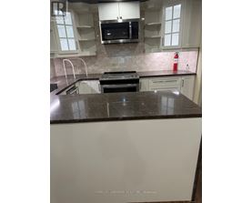 A kitchen with white cabinets and a black counter top.