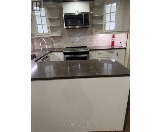 A kitchen with white cabinets and a black counter top.