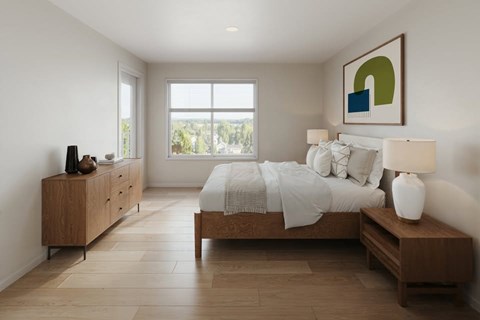 A bedroom with a large bed, a wooden dresser, and a window with a view of trees.