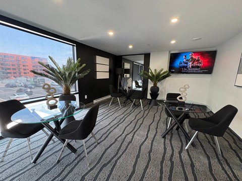 A modern living room with a glass table and black chairs.