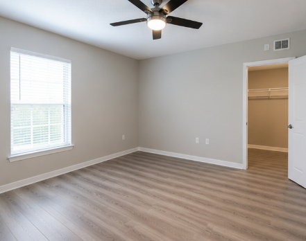 A room with a ceiling fan and a window with blinds.