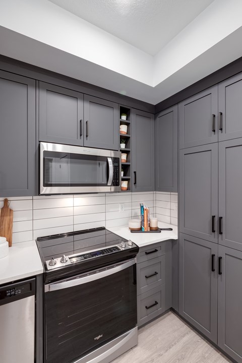 A modern kitchen with a black oven and microwave above a white counter.
