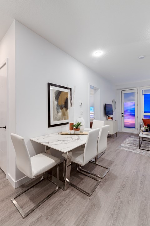 A modern dining room with a white table and chairs.