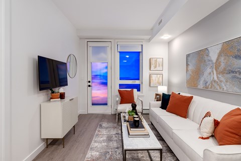 A living room with a white couch and a television on the wall.