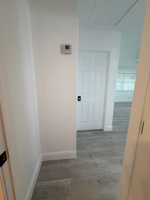A white door is in a room with a light switch on the wall.