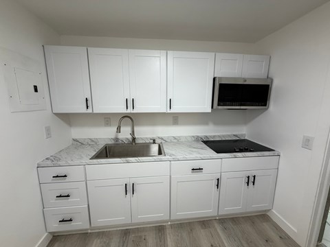A kitchen with white cabinets and a marble countertop.
