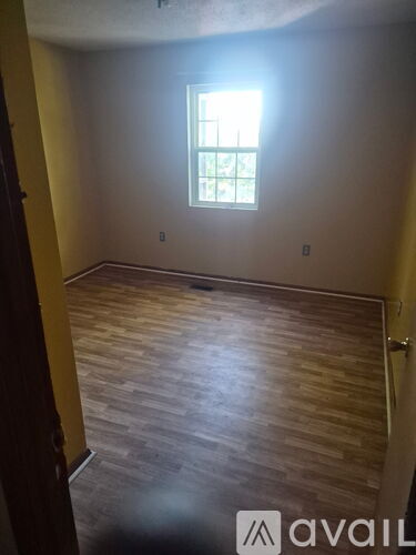 A room with wooden flooring and a window.