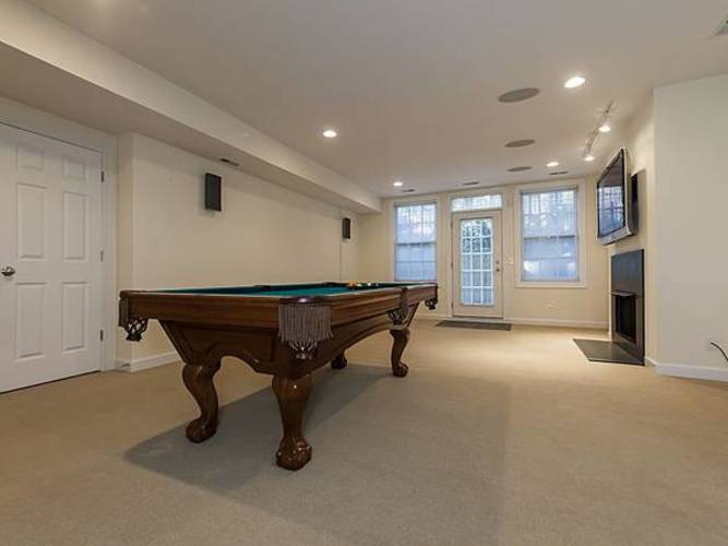 A pool table is in the middle of a room with a door on the left and a window on the right.