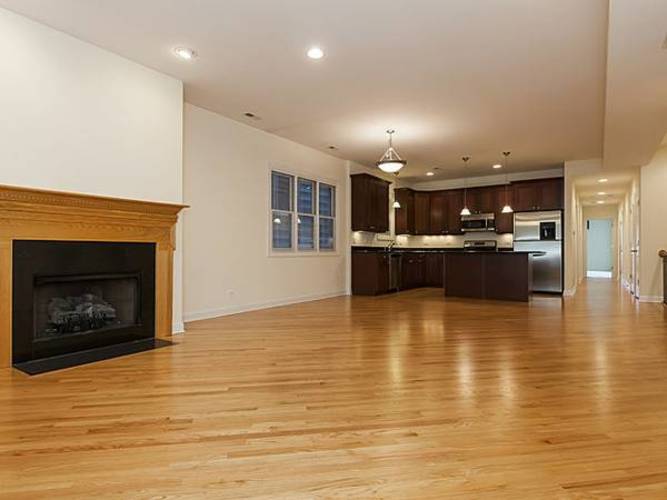 A large open living room with a fireplace and wooden floors.