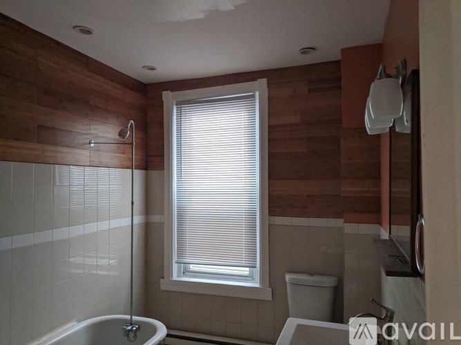 A bathroom with a wooden wall and a white toilet.