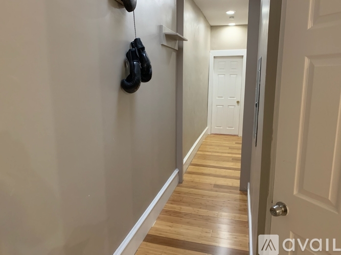 A pair of black shoes is hanging on a hook on a white wall.
