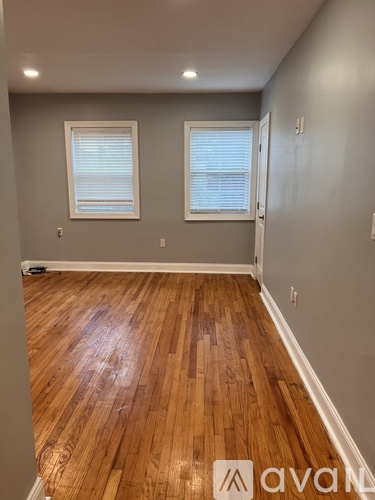 A room with wooden floors and two windows.