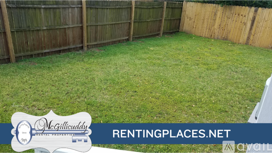 A backyard with a wooden fence and green grass.