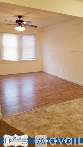 A room with a ceiling fan and wooden flooring.
