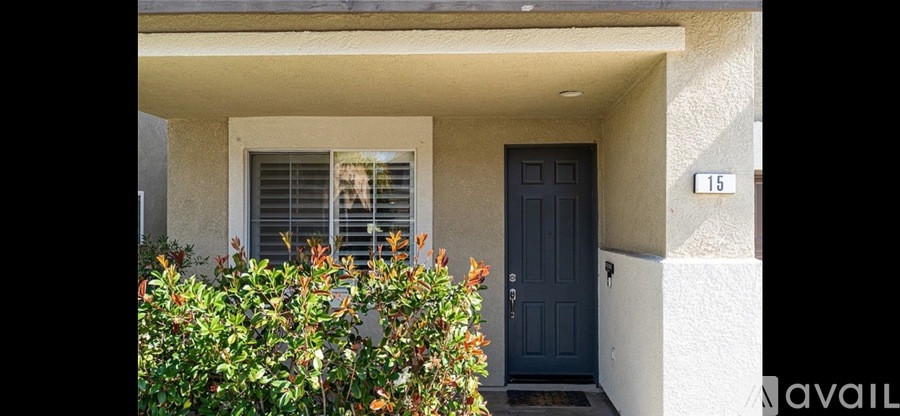 A house number 15 with a dark blue door and a window with white blinds.