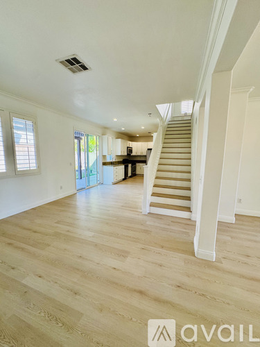 A spacious room with wooden flooring and a staircase leading to another level.