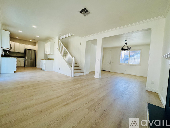 A spacious living room with wooden flooring and a staircase leading to the upper level.