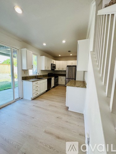 A modern kitchen with white cabinets and a wooden floor.