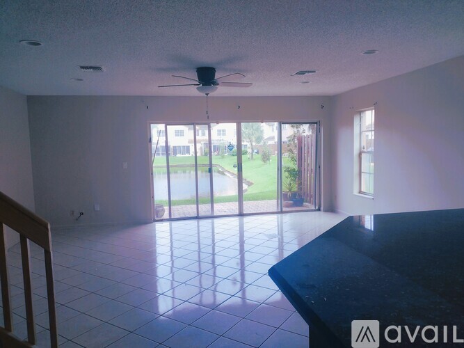 A spacious room with a ceiling fan and sliding glass doors leading to a backyard.
