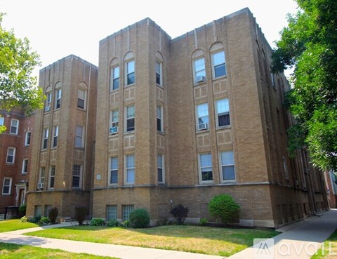A large brick building with many windows and a green lawn in front.