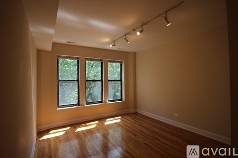 A room with wooden floors and a large window with a view of trees.