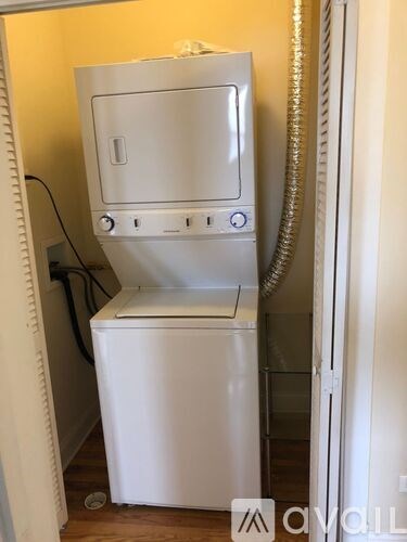 A white dishwasher is in a narrow space between a wall and a door.