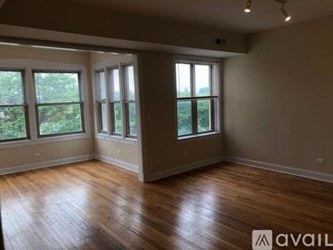 A room with wooden floors and three windows.