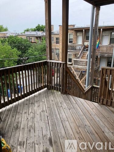 A wooden deck with a railing and a view of apartment buildings.