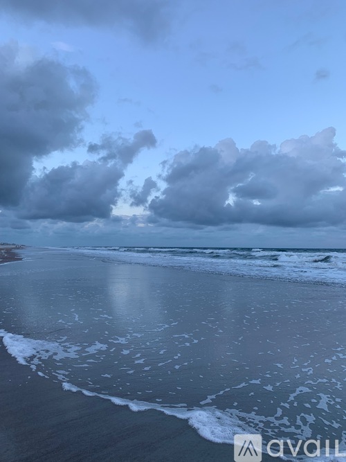 A beach with waves coming in and a cloudy sky.